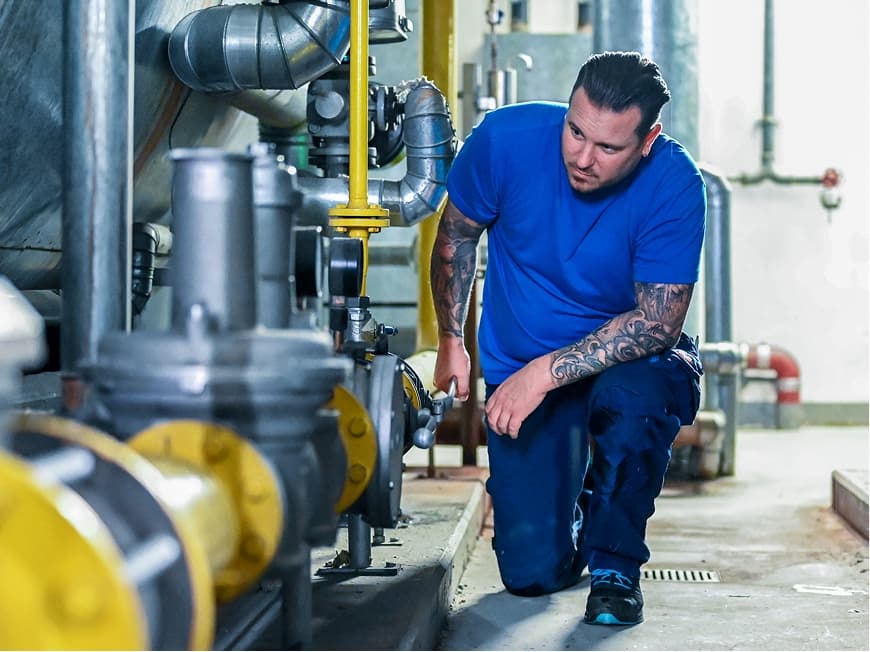 Ein Anlagenmechaniker überprüft eine große Maschine im Keller des Kliniums