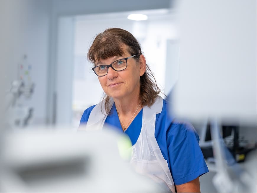 Eine Pflegefachfrau steht am Krankenbett auf der Intensivstation und versorgt den Patienten