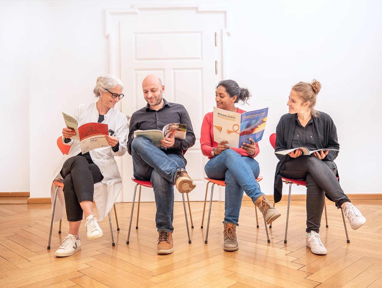 Vier Pflegefachpersonen sitzen in einer Stuhlreihe und tauschen sich zu einer aktuellen Studie aus