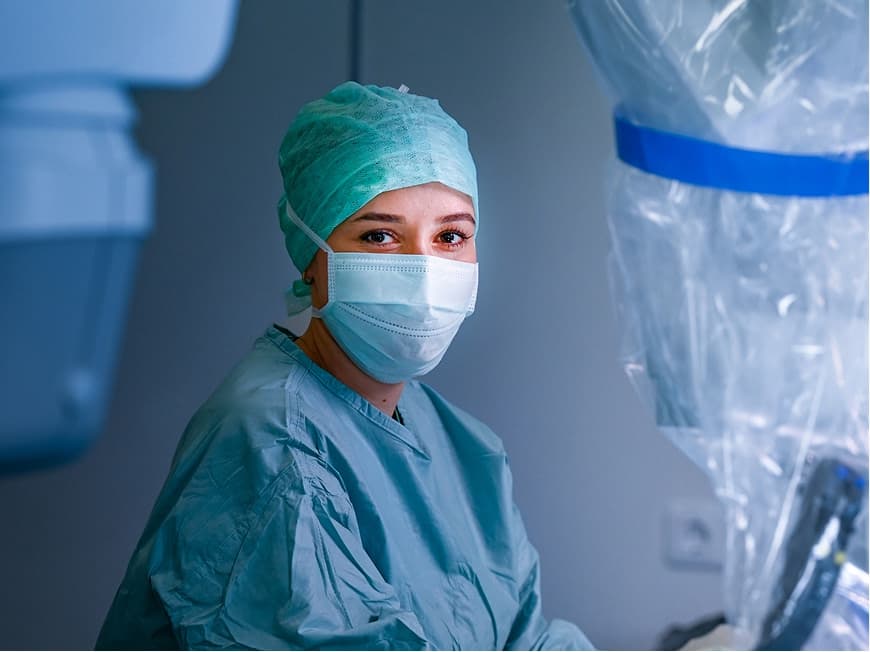 Eine Operationstechnische Assistentin blick während einer OP in die Kamera