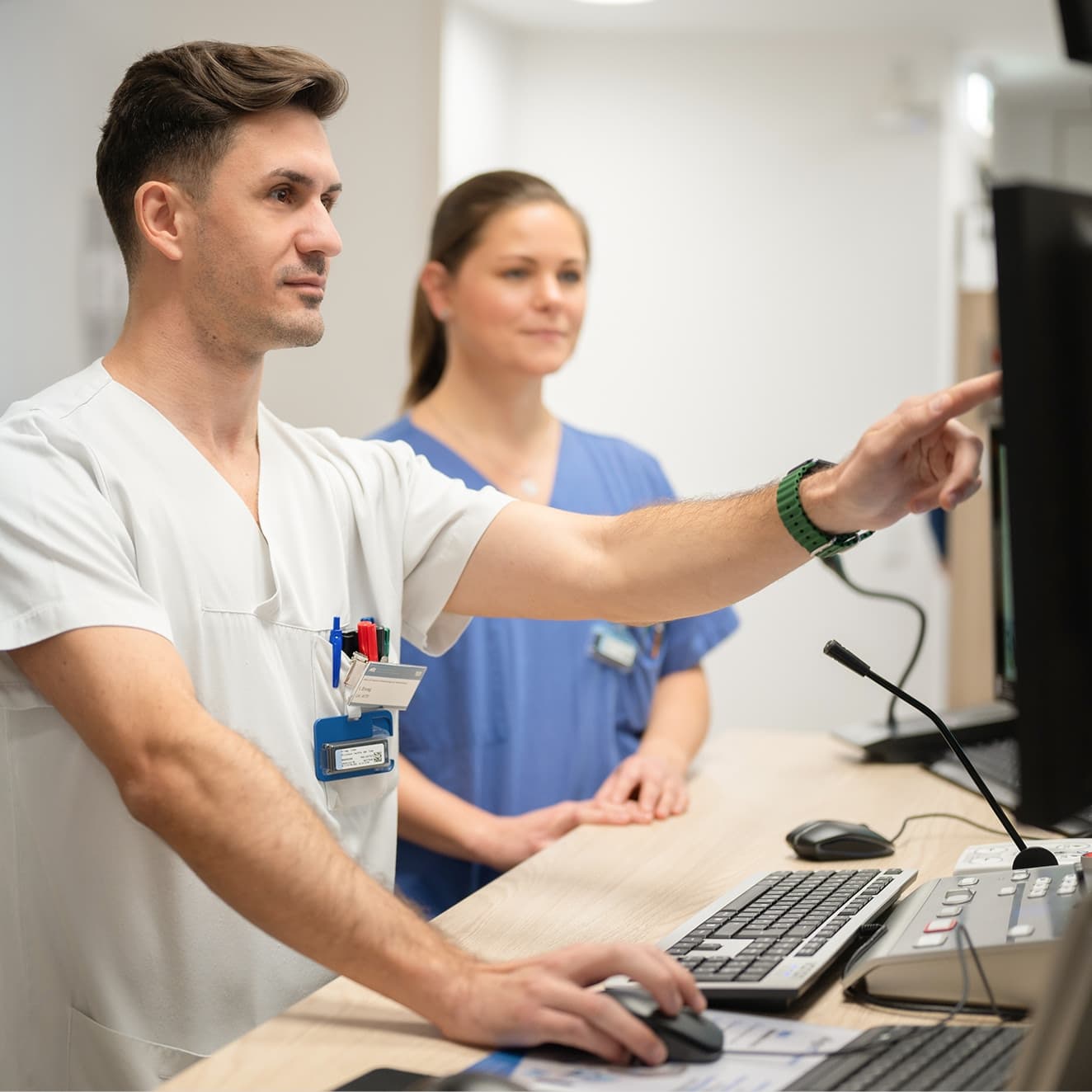 Ein Medizinischer Technologe für Radiologie bespricht mit einer Kollegin MRT Bilder am Bildschirm