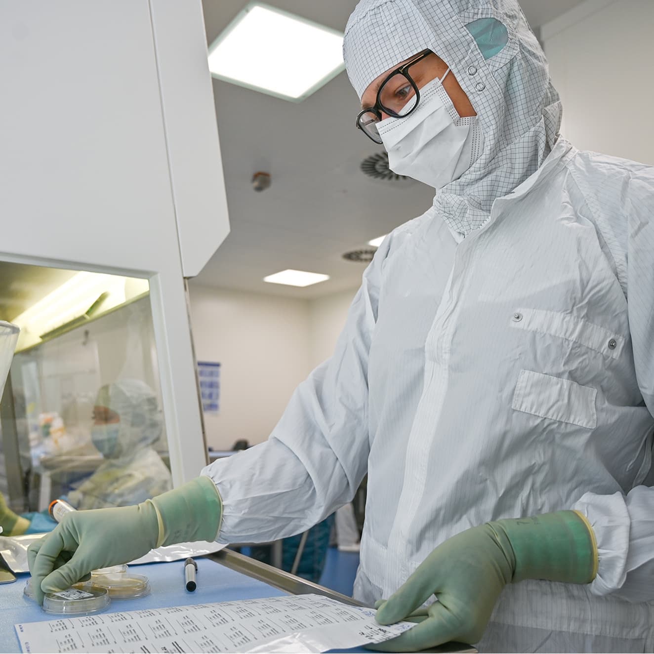 Eine Pharmazeutisch-kaufmännische Angestellte stellt Medikamente im Reinraum her
